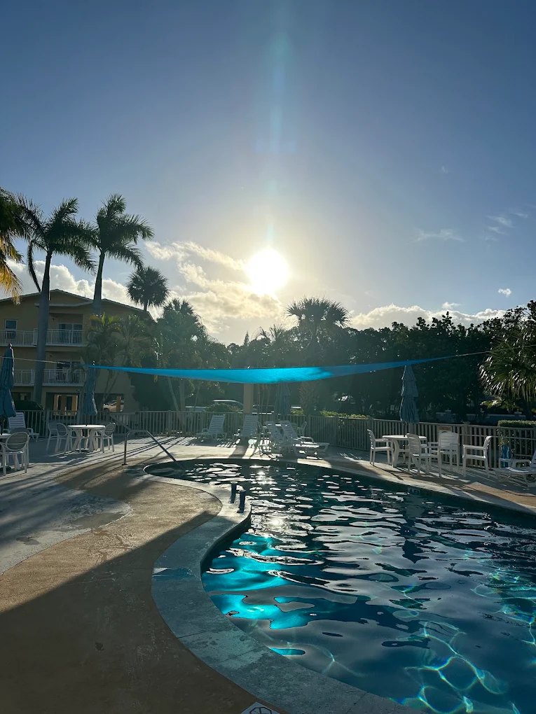 Heated pool at Port Largo Villas under a blue shade sail with palm trees and lounge chairs