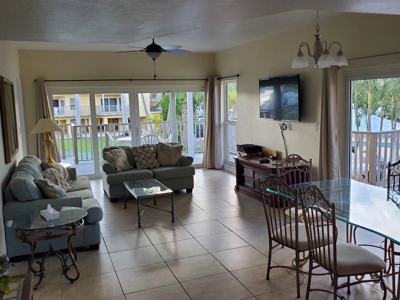 Villa living and dining room with tile floors, sofas, and sliding glass doors opening to the deck